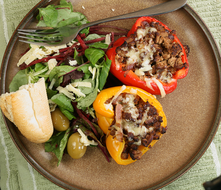 two roast stuffed peppers wit side salad and crusty breadの写真素材