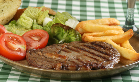 juicy grilled ribeye beef steak with golden fries and saladの写真素材