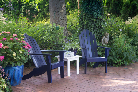 A wooded garden patio with potted hydrangia next to two blue wooden chairs.の写真素材