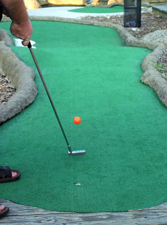 A man putting a mini-golf ball.の写真素材