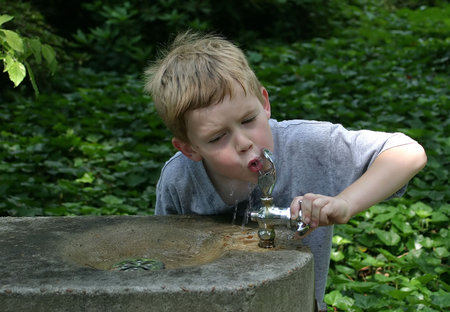 A little boy drinking from a water fountain.の写真素材