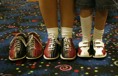 Three pair of bowling shoes. Two being worn, one empty.の写真素材
