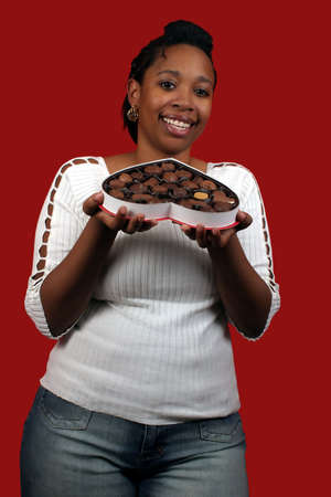 A pretty young woman holding a box of valentine candy.の写真素材