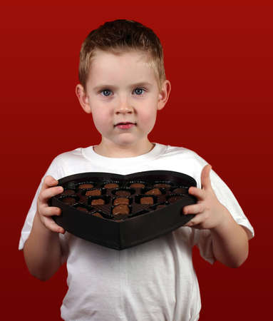 A little boy holding a heart shaped box.の写真素材
