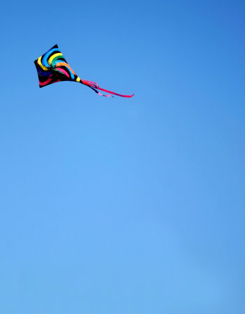 A colorful kite in a bright blue sky.