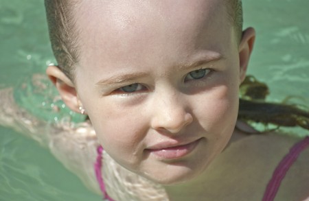 Young girl swimming in a pool in the heat of the summer.の写真素材
