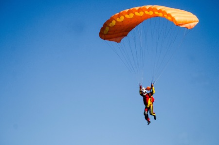 parachutists come in the land on a beautiful orange parachuteの写真素材