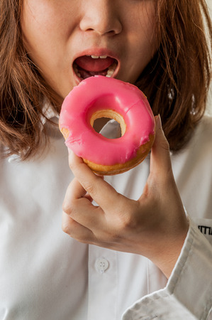 The girl is eating pink donut の写真素材