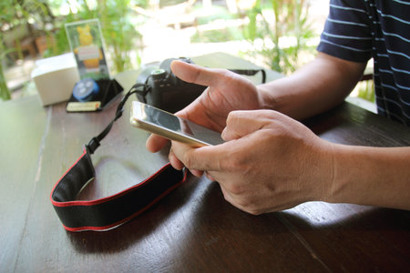 A hand holding a smartphone has a camera in a coffee shop.