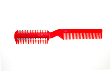 Comb with blade for cutting hair on a folk background.