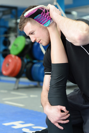 Personal trainer helping young woman in gym with stretching exercisesの写真素材