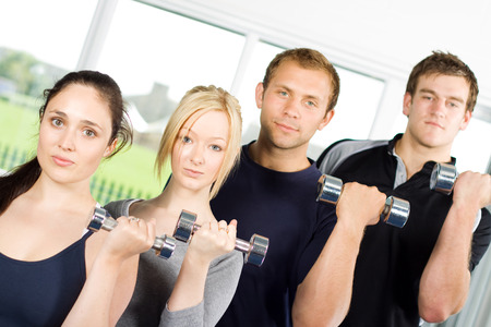 Group of young people lifting weights in the gymの写真素材
