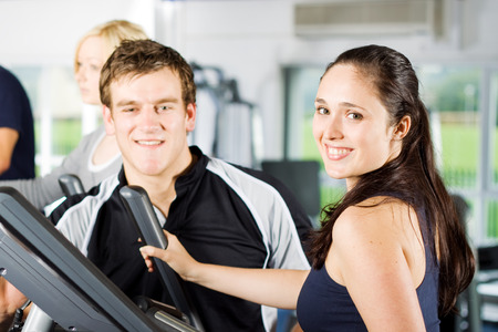 Personal trainers in the gym giving instruction and help to attractive young womenの写真素材