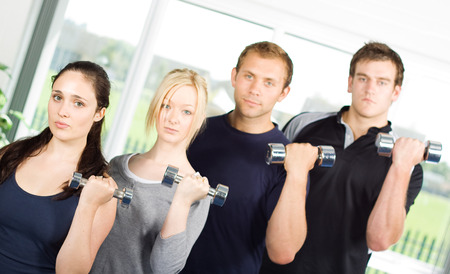 Group of young people lifting weights in the gymの写真素材