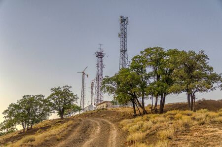 Radio towers standing on a hill at sunsetの写真素材