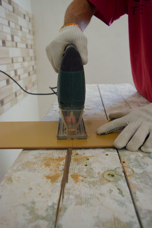 The man cuts the laminate panel with an electric jigsaw.の写真素材