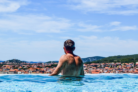 The man in the pool against the backdrop of the sea and islands.の写真素材
