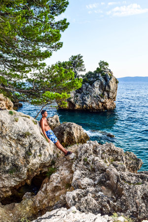 The man at sunset near the rock Brela. Punta Rata beach, Croatia.