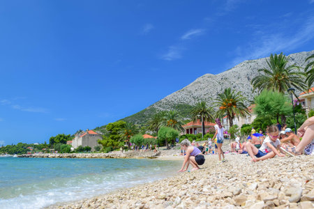Orebic, Croatia - July 17, 2018: Vacationers on the beautiful pebble beach.