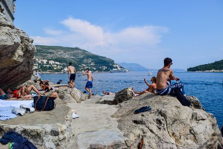 Dubrovnik, Croatia - July 26, 2018: Tourists on a rocky beach near the old town of Dubrovnik.のeditorial素材