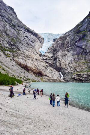 Brikdalsbre, Norway - June 25, 2019: Tourists near the Brikdalsbreen glacier, which is the sleeve of large Jostedalsbreen glacier. Melting glacier forms the Briksdalsbrevatnet lake with clear water. Norway.のeditorial素材