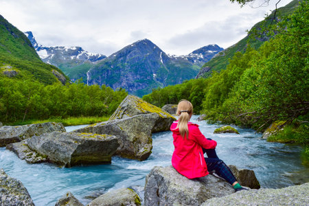 The young woman near river which is located near path to the Briksdalsbreen (Briksdal) glacier. The...