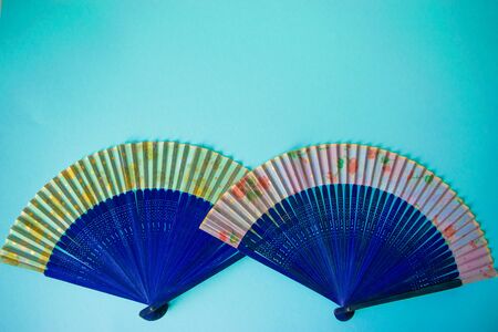 Composition of navy blue female hand fans close-up on the light blue paper background. Subject photo for design with copy space in minimal style, template for lettering or text.の写真素材