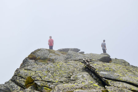 Guys stand on top surrounded by fog and low clouds near Transalpina road. This is one of  most...
