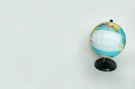 Earth globe is wearing a protective mask, as a symbol of the fact that all people of the entire planet are quarantined due to the epidemic and pandemic of Coronavirus. Copy space, banner or template.の写真素材