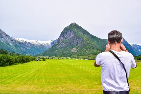 Tourist take a photo of mountain landscape and glaciers of Jostedalsbreen National Park from the Glacier Museum (Bremuseum) in Fjaerland. Sogn og Fjordane. Norway.の写真素材