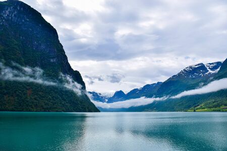 Landscape of beautiful Oldevatnet glacial lake and foggy mountains in which there are glaciers of Jostedalsbreen National Park. Norway.の写真素材