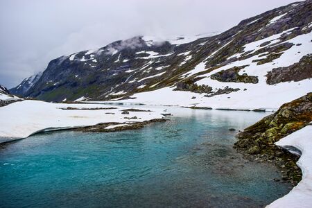 Mountain landscape with the lake formed by melting snow. Global warming and climate change, reducing snow cover and glaciers.の写真素材
