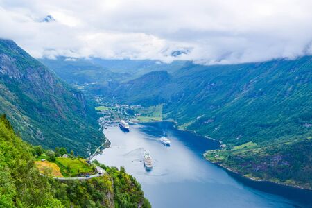 The cruise liners at the end of Geirangerfjord, near small village of Geiranger. View from Eagles Road. Fjord and mountains landscape in cloudy weather. Summer travel adventure to Norway.の写真素材