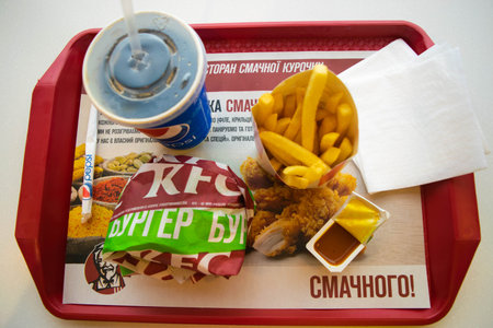 Kiev, Ukraine - March 8, 2020: Food and drink in a popular fast food restaurant KFC. Is popular fast food chain known as Kentucky Fried Chicken. Potato fries, Pepsi and burger with curry sauce.のeditorial素材