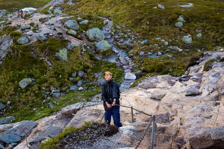 Chains on the way to famous Kjeragbolten help tourists climb steep cliffs. Kjeragbolten is a rock stuck between two mountains above the Lysefjorden on Mount Kierag in municipality of Forsand, Norway.の写真素材