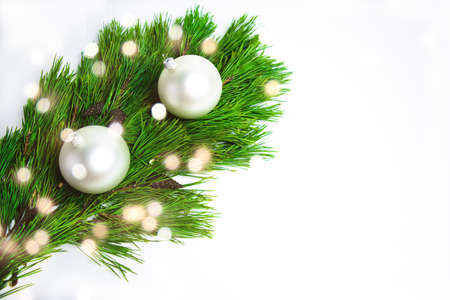 White balls and green pine branches close up with bokeh on white background. Christmas or New Year holiday greeting card. Copy space, template for lettering or text. Selective focus.の写真素材