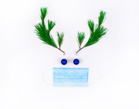 Christmas deer in a medical protective mask. Deer head made of pine branches and Christmas balls on...