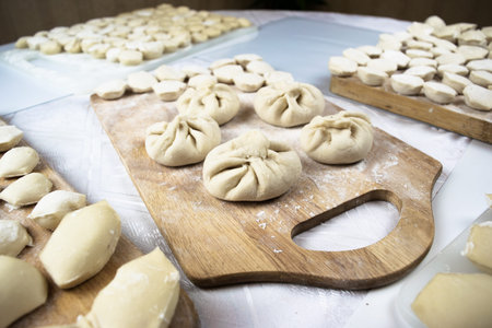 Handmade dumplings, ravioli and khinkali are beautifully laid out on chopping boards sprinkled with...