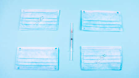 Vaccine shortage problem. Masks, syringes and vaccine vials move on a light blue background.の写真素材