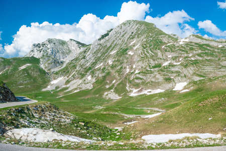 Mountains peaks and snow of Durmitor National Park, along which picturesque high-mountain tourist road of northern Montenegro passes.  site. Beautiful summer sunny and cloudy landscape.の写真素材