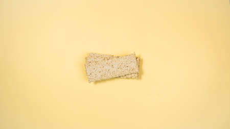 Rectangular whole grain crispbreads on yellow background with copy space. A healthy, nutritious yeast-free snack. Minimal healthy nutrition concept. Flat lay.の写真素材