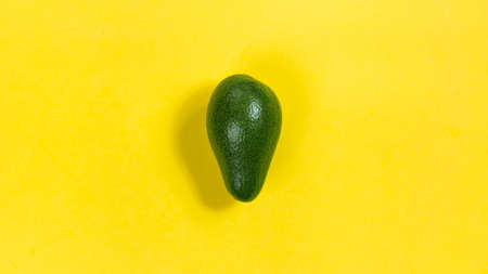 Green ripe avocado on a yellow background close-up. Concept of proper nutrition and healthy fruits. flat lay.の写真素材