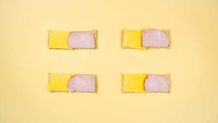 Four rectangular sandwiches with cheese and ham from whole grain crispbread. A healthy, nutritious yeast-free snack. Minimal healthy nutrition concept. flat lay.の写真素材