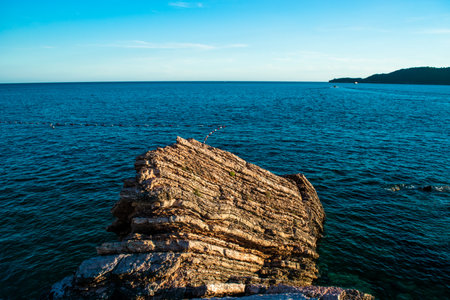 Beautiful rocks on pebble public stone beach. Rafailovici esort towns. Mountenegro. Adriatic Sea. Summer sunny day. Seaside vacation concept.の写真素材