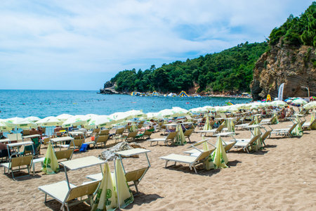 Morgen beach, Montenegro - July 4, 2021: Sun loungers and umbrellas on the sandy beach located near the city of Budva. summer sunny landscape.のeditorial素材