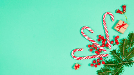 Candy canes and fir branches are decorated with red berries and small gift boxes. Turquoise...