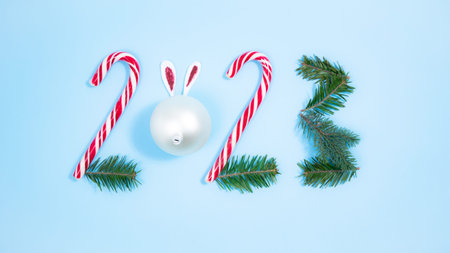Numbers 2023 made from candy canes, a white Christmas ball and spruce branches. Symbol of New Year....