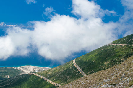 White fog high in the mountains on the Llogara pass. View from the highlands on serpentine road to the pass.Landscape of Albanian Riviera, Palasa beach and white clouds against a blue sky. Albania.の写真素材