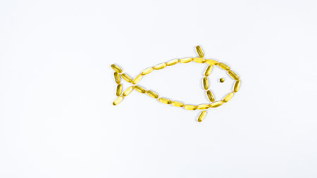 <p>Fish made from yellow transparent capsules with fish oil, Omega 3. White background. Concept of maintaining and improving health.</p>の写真素材