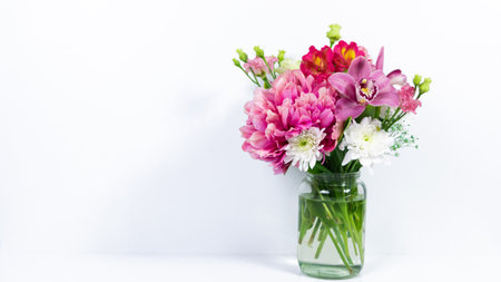 Bouquet of various natural flowers in a glass jar on a white background. Greeting card for birthday, mother's day, women's day or other occasion. copyspace.の写真素材